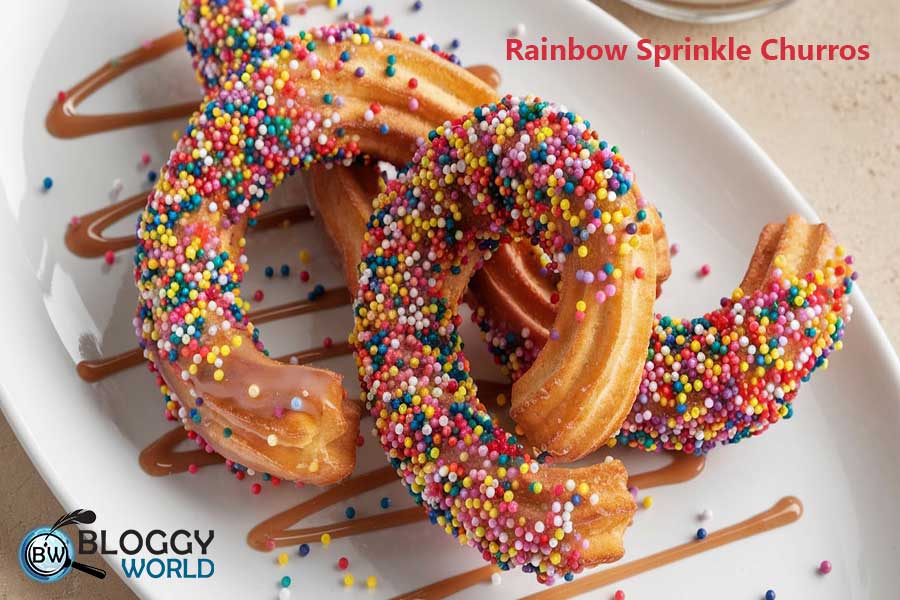 Tray of churros coated with rainbow sprinkles, a colorful treat for kids.