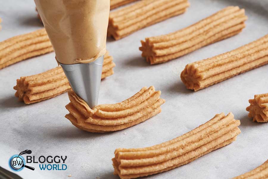 Tray with parchment paper and freshly piped churros ready for frying.
